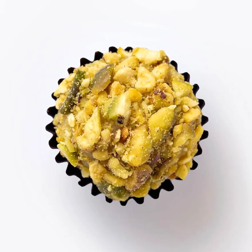 Brigadeiro de pistache coberto de pistache picado, visto de cima, na forminha